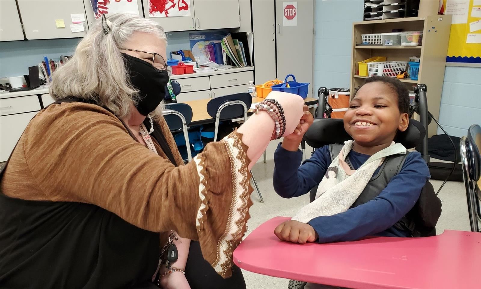 A teaching assistant gives a student a fist bump 
